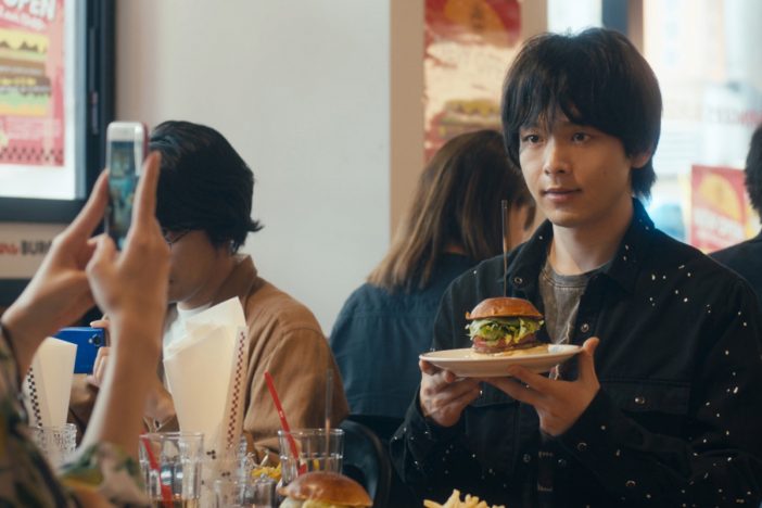 中村倫也がハンバーガーを持って写真撮影　『人数の町』新場面写真公開